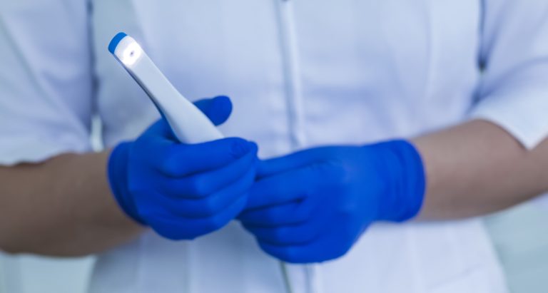 Intraoral Camera held by a dental assistant wearing blue medical gloves
