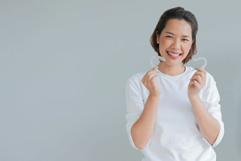 woman holding Invisalign clear aligners